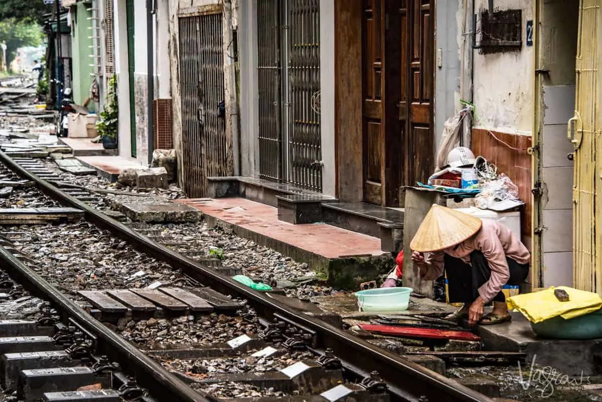 Lady washing dishes next to the train tracks in train street.