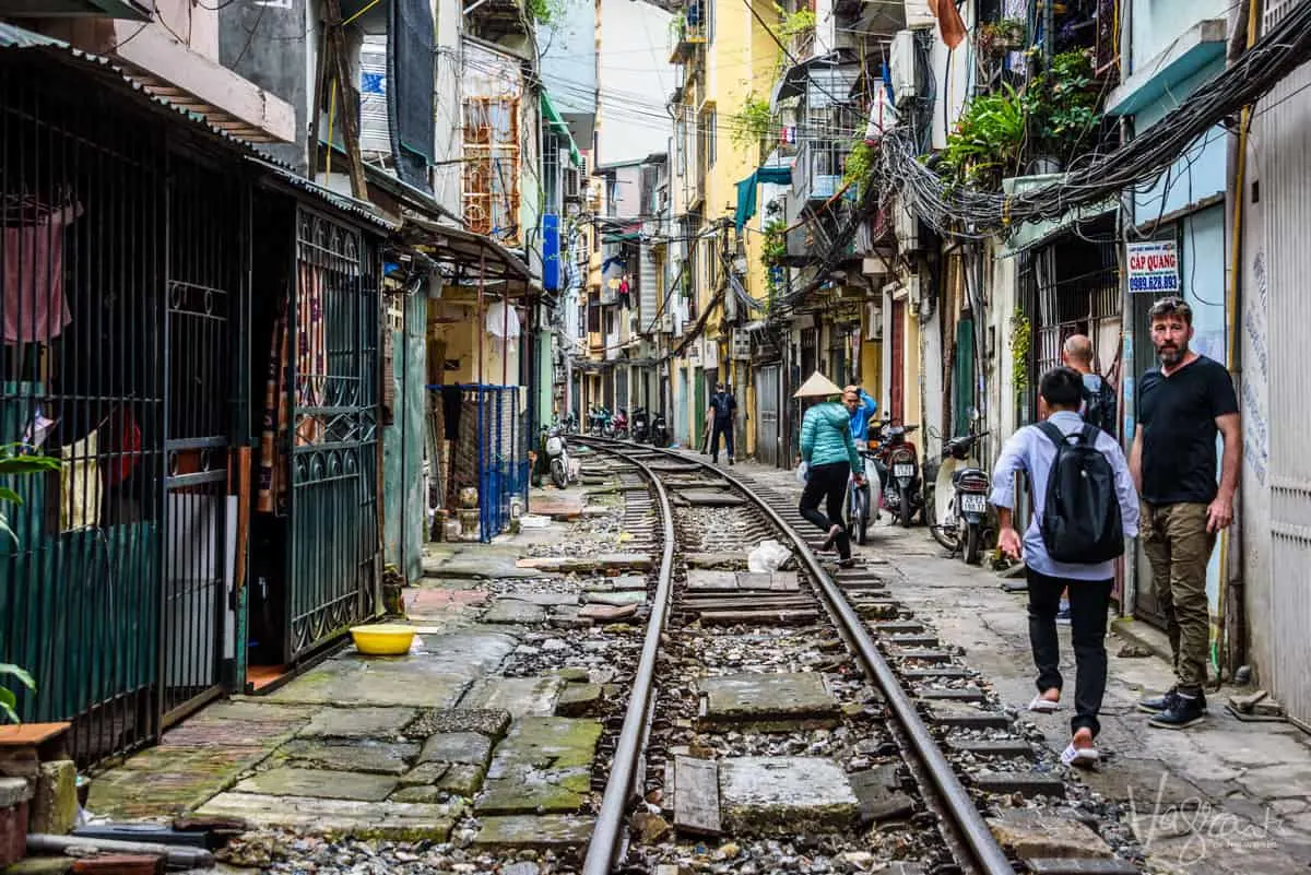 People walking next to the tracks on train street, one of the most popular things to see and do in Hanoi Vietnam.