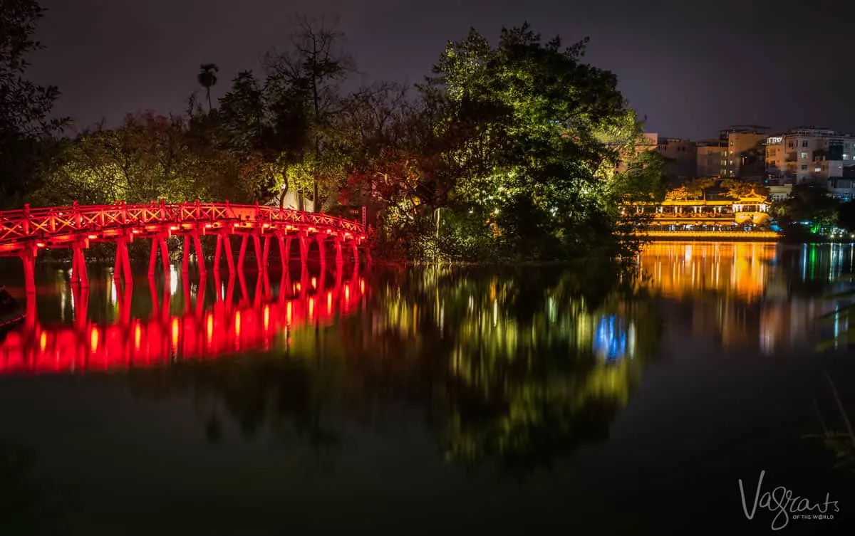 Bridge lit red crossing turtle lake in Hanoi Old Quarter.