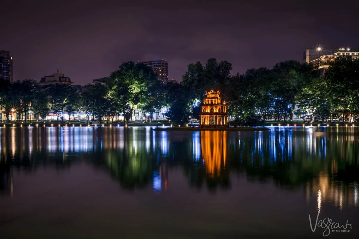 Turtle tower lit with golden light, spending time around this lake is the best thing to do in Hanoi at night.