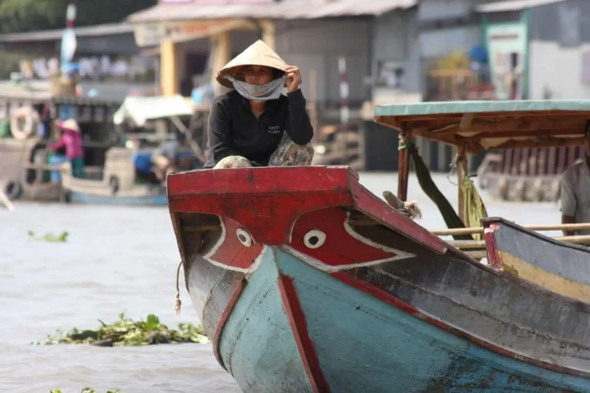 women in conical hat sitting on the bow of a junk on the mekong delta. The best day trips from ho chi minh city vietnam