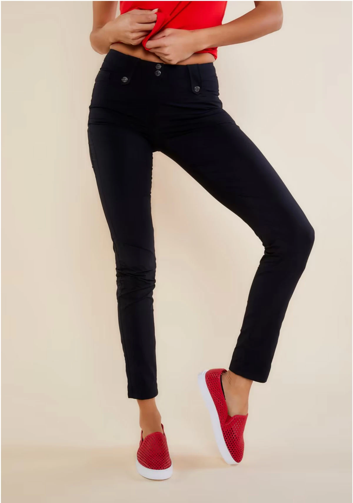 Lady modelling a pair of navy travel pants with red shoes and red T shirt.