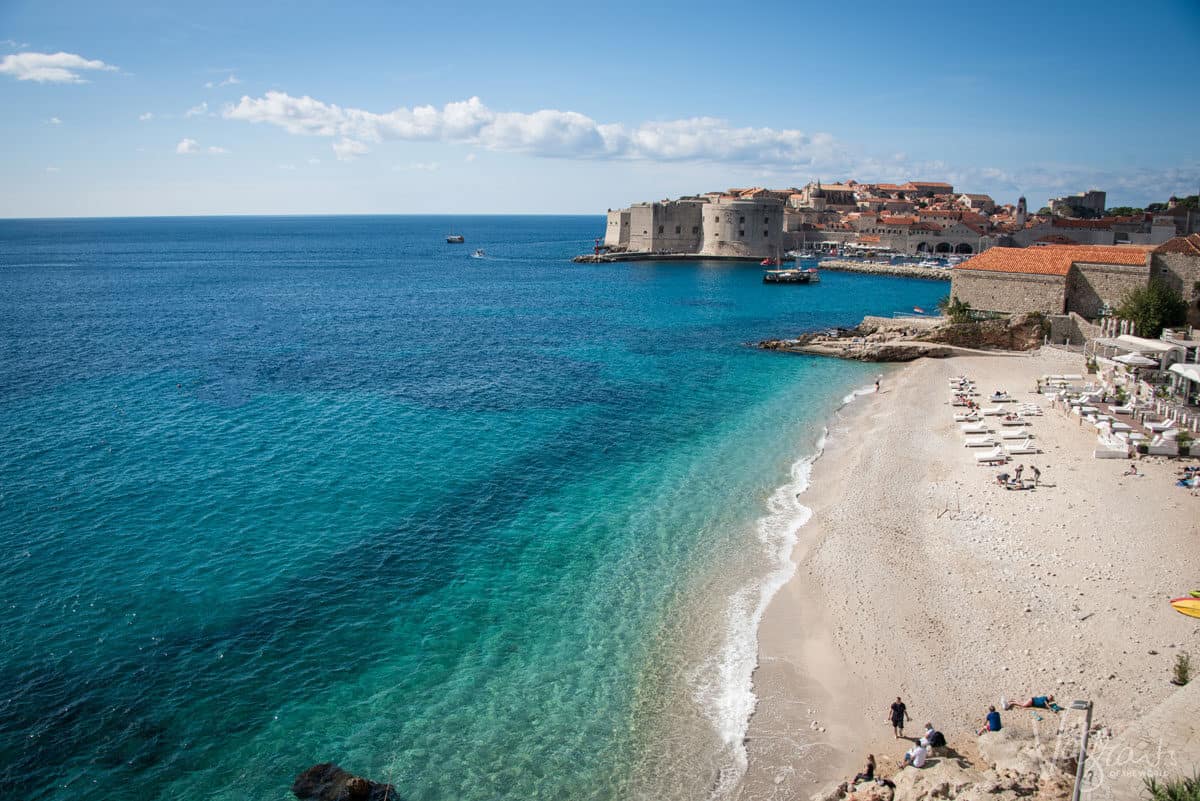 The beach and blue ocean in front of the walled city of Dubrovnik in Croatia