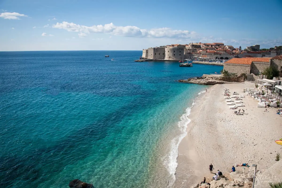 The beach and blue ocean in front of the walled city of Dubrovnik in Croatia