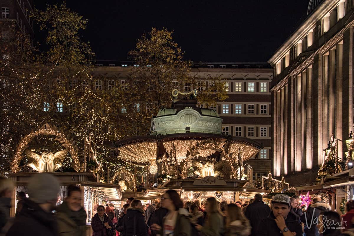Crowds making their way past a carousel at Christmas markets.