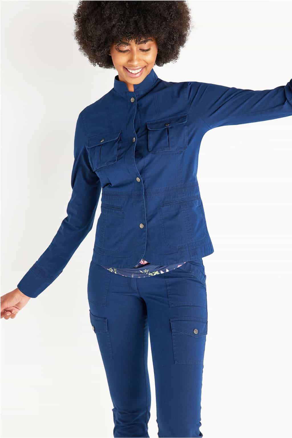 Attractive dark lady with a large afro modelling a blue denim travel outfit with her arms stretched out in a playful fashion. 