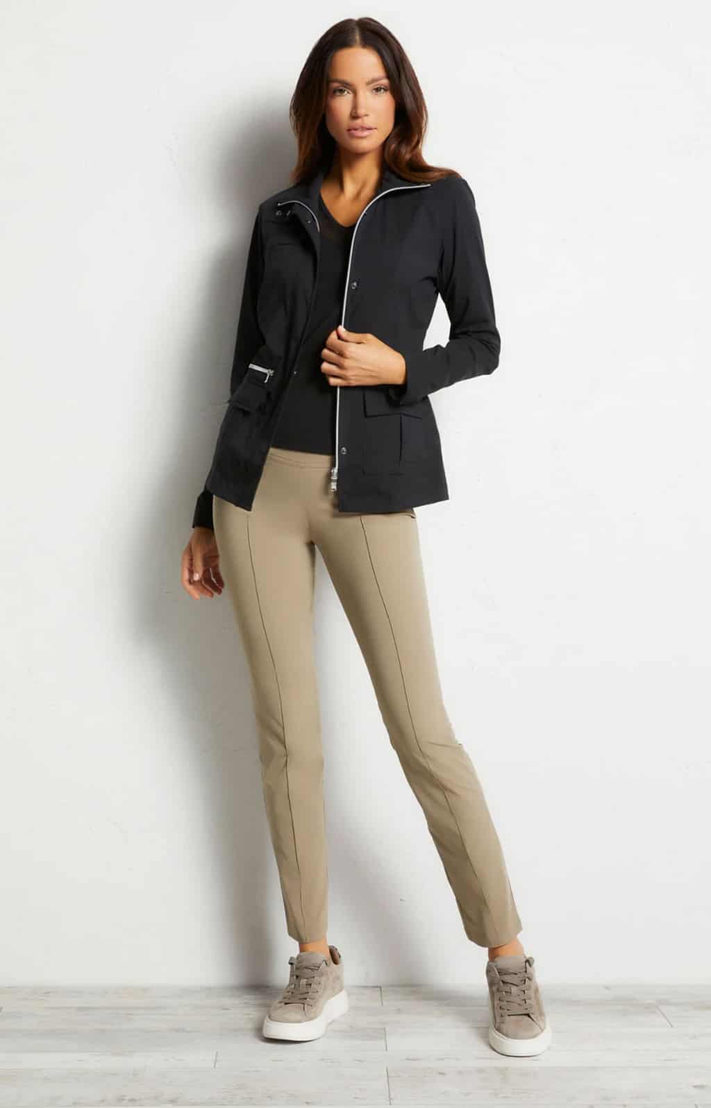 Attractive woman modelling a travel jacket in black with tan pants.