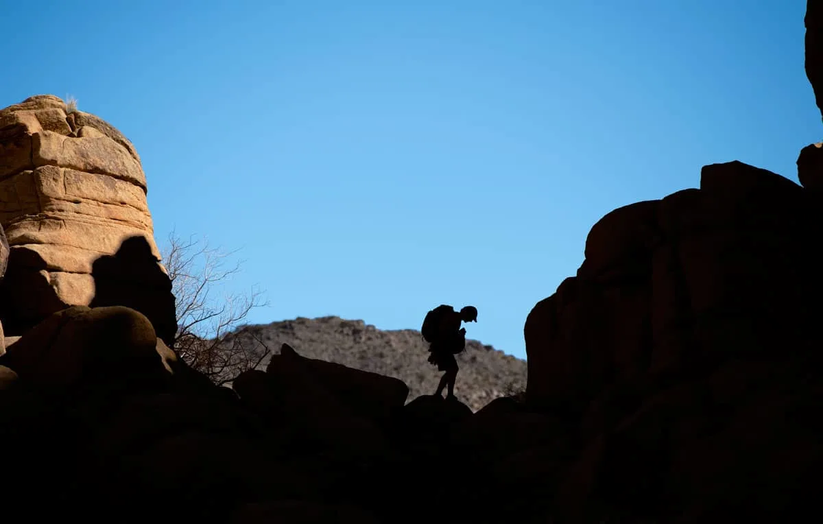 Silhouette of a man hiking through rocks in Joshua Tree National Park