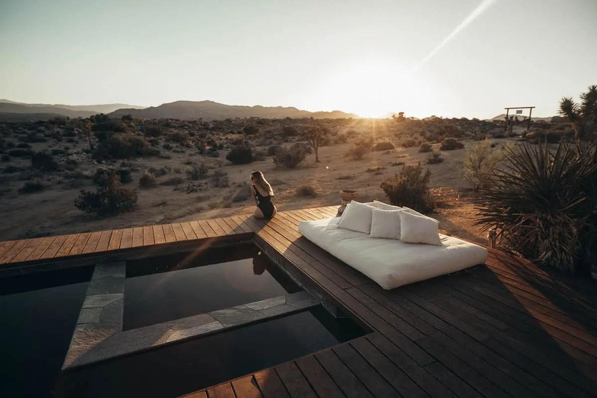 Lady sitting on the edge of a pool overlooking the desert in Joshua Tree USA. There is lots of luxury accommodation in Joshua Tree for those who want to indulge in the desert. 
