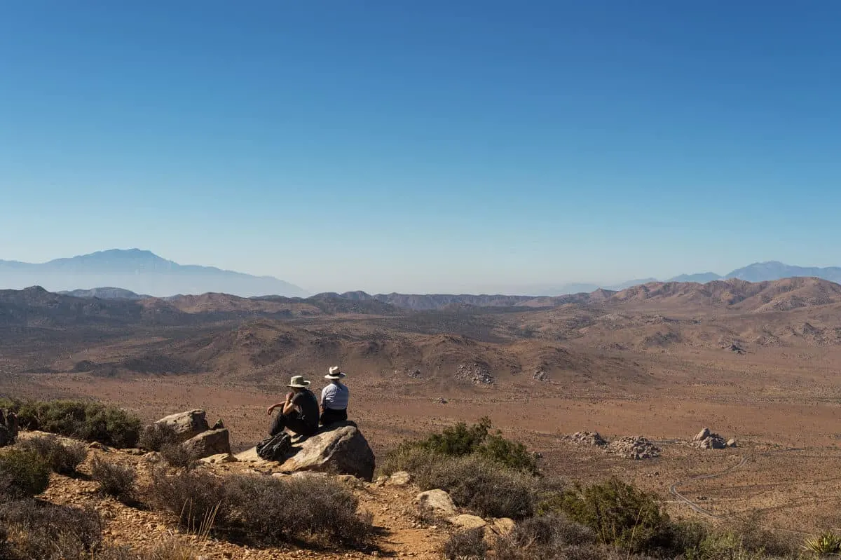 Two people sitting at the top of Ryan Mountain Summit, one of the most popular hikes in Joshua Tree National Park