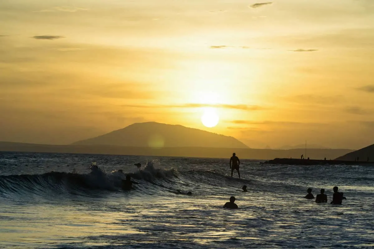 Surfers riding waves at sunset in Mui Ne Vietnam