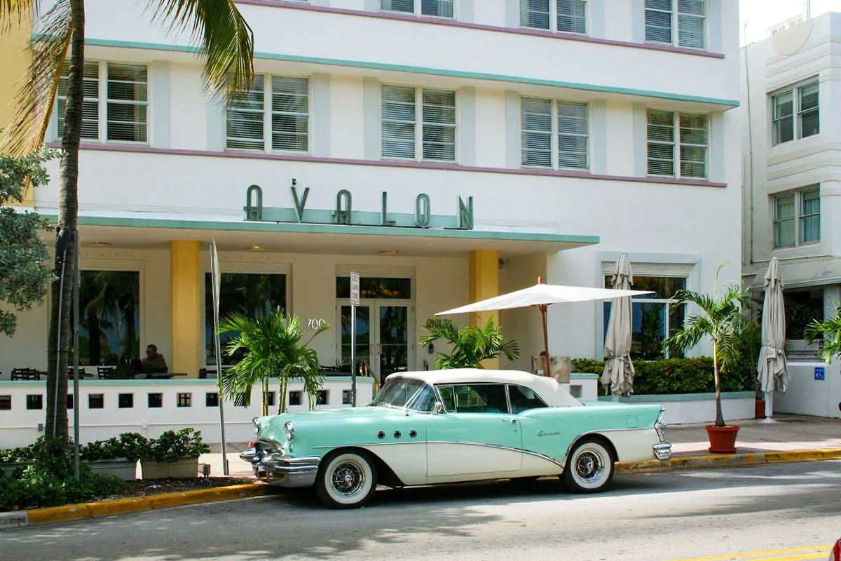 Vintage blue and white car parked in front of an art deco hotel in Miami Beach 