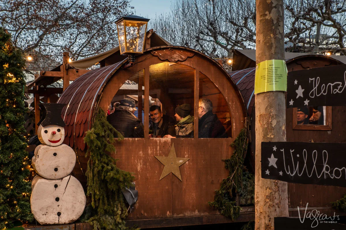 people sit cosily in little wooden chalet nooks enjoying the festive fare offered at Europe's best Christmas markets. These are the kind of experiences you can expect on a Christmas market cruise