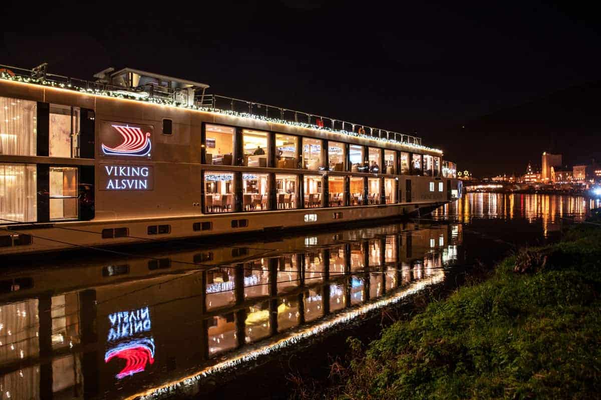 A viking river cruises ship sits docked at night lit up with christmas lights. You can expect beautiful scenes like this on Viking Christmas cruises thanks to the shorter days.