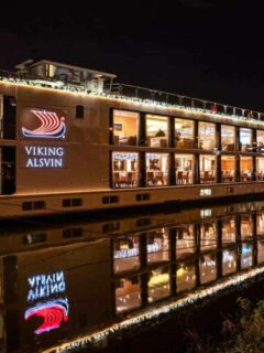 A viking river cruises ship sits docked at night lit up with christmas lights. You can expect beautiful scenes like this on Viking Christmas cruises thanks to the shorter days.
