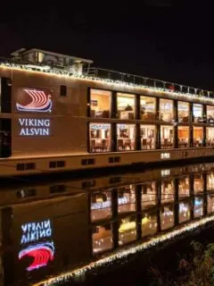A viking river cruises ship sits docked at night lit up with christmas lights. You can expect beautiful scenes like this on Viking Christmas cruises thanks to the shorter days.