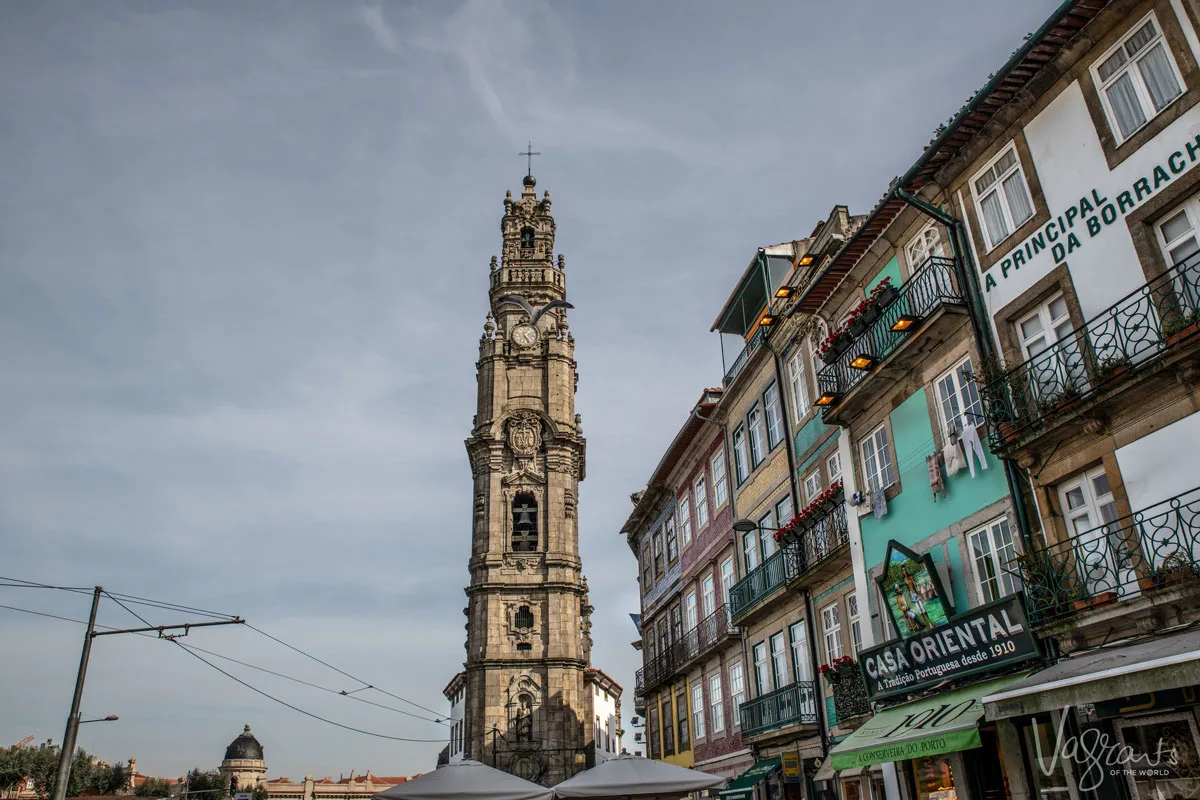 The Torre dos Clérigos on the skyline of Porto with classic colourful buildings framed to the right.
