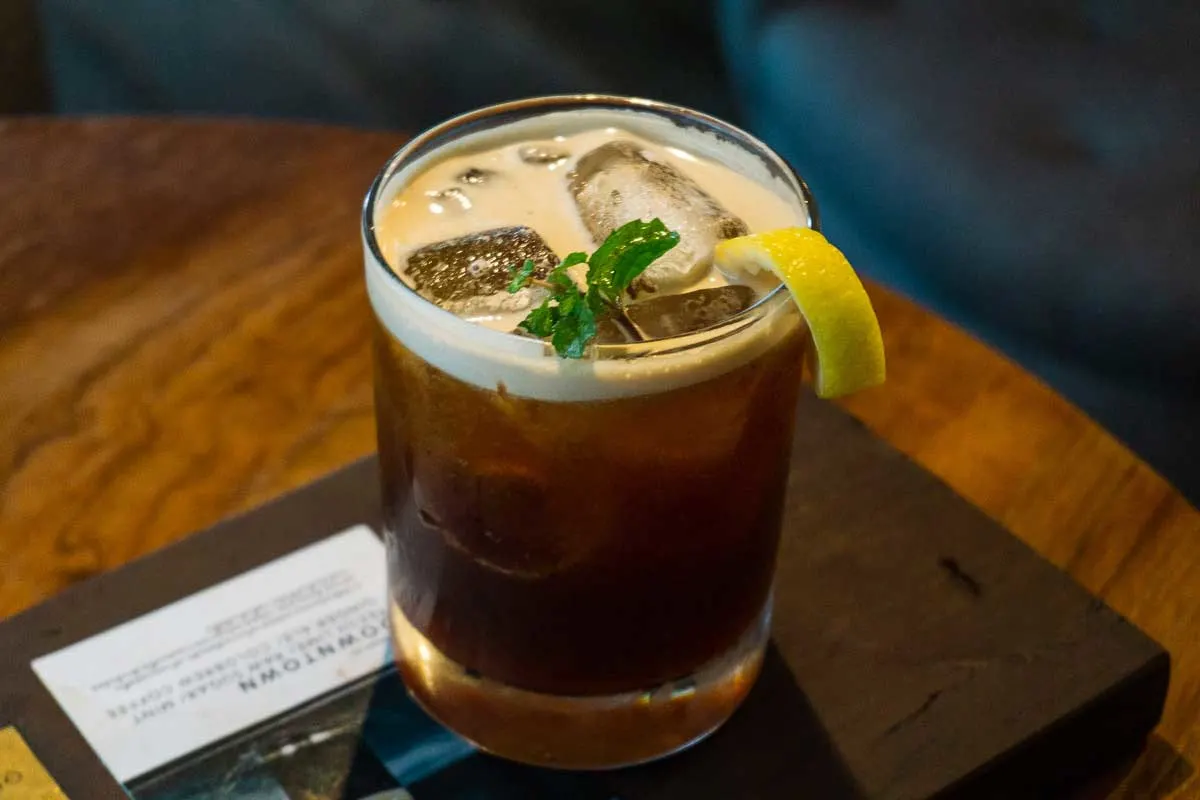 Ice coffee in a glass with a lemon wedge and sprig of mint. The type of coffee you can expect to find in Chiang Mai