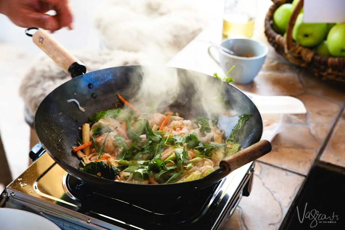 Thai food being cooked quickly in steaming hot wok. A Thai cooking class is a great addition to any any 3 days in Chiang Mai