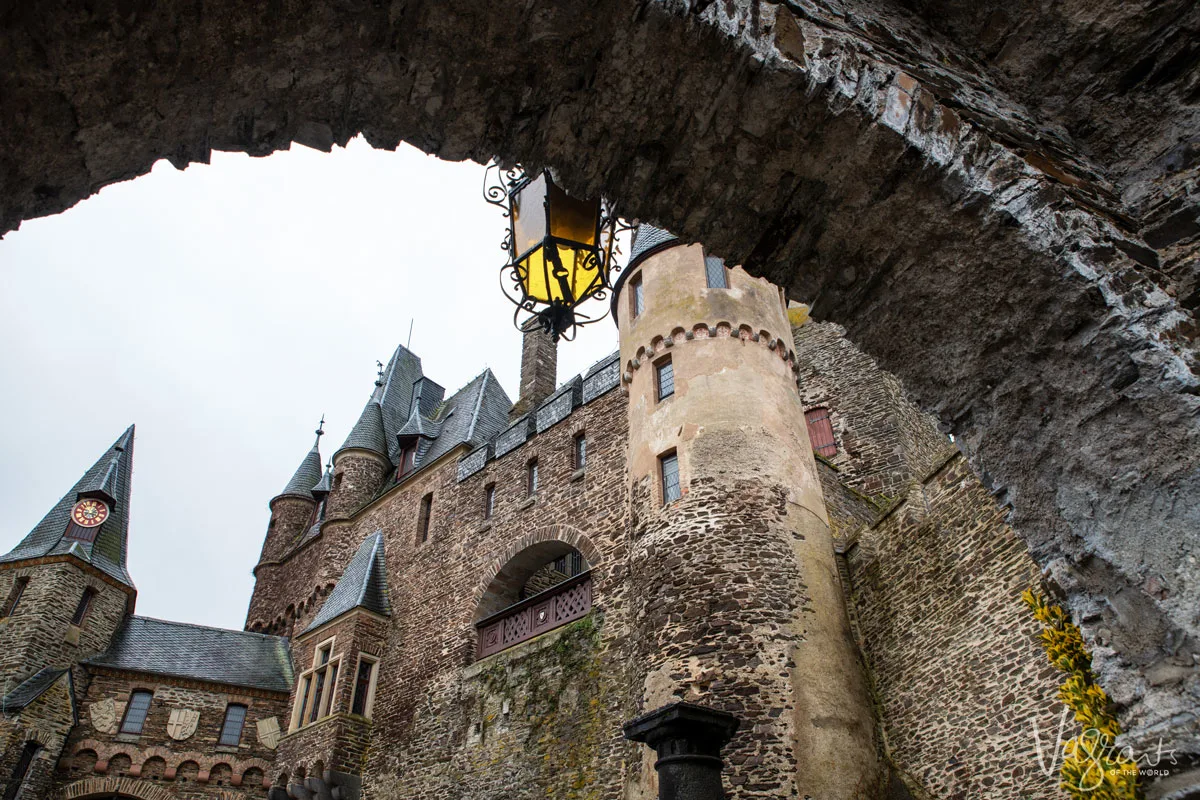 Looking up at Reichsburg Castle through a stone arch. One of the famous fairytale castles to see on the Moselle and Rhine regions of Germany on a Christmas market river cruise. 