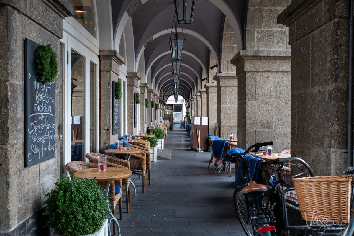 Looking down an arched walkway lined with cafe chairs in the historical centre of Koblenz Germany