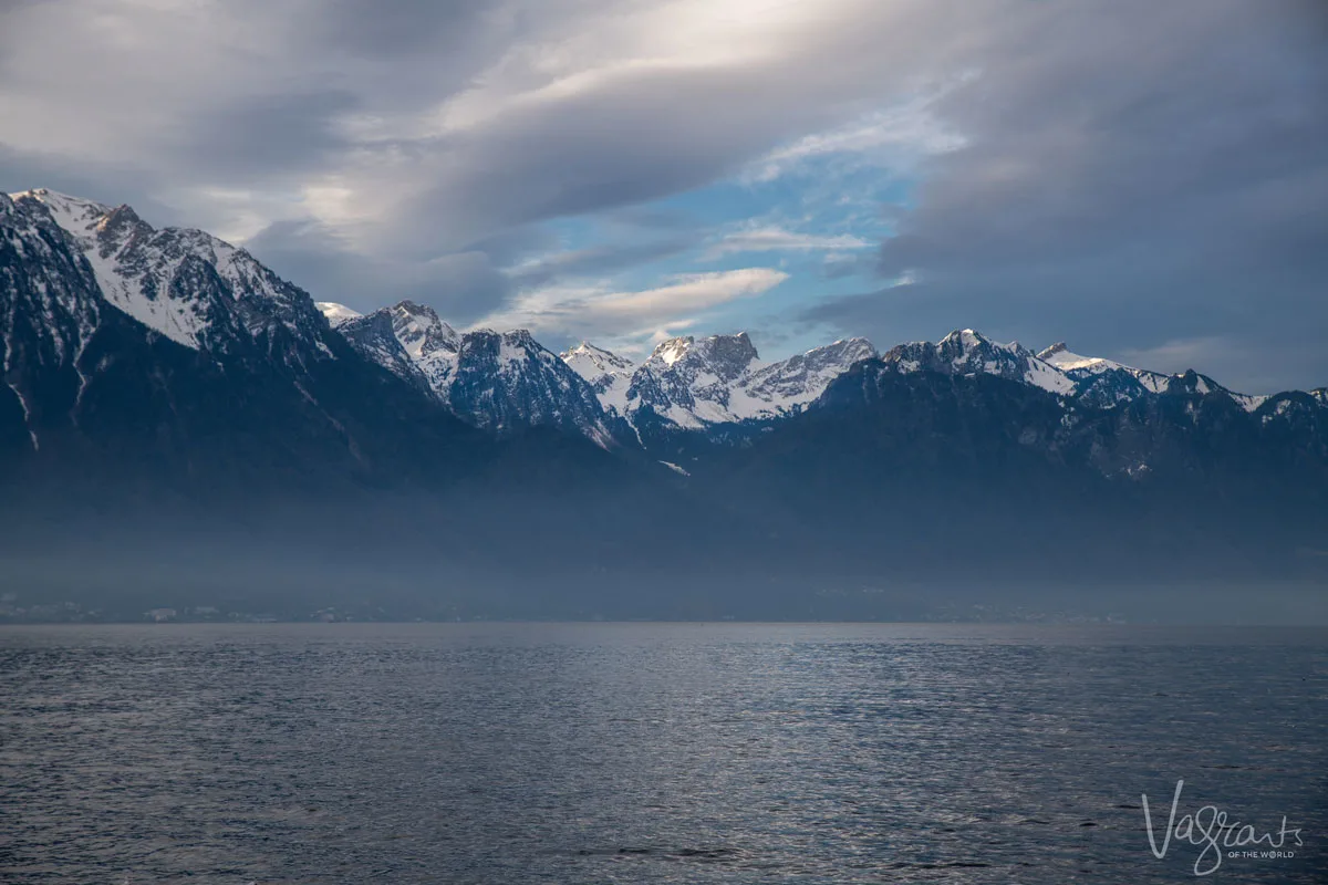 Lake Geneva with mist on the water and the sun breaking through the clouds over the Swiss Alps