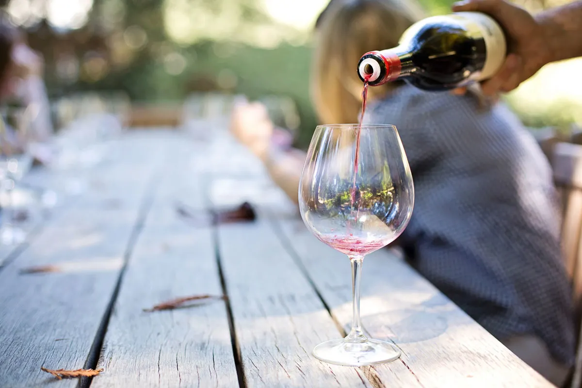 Glass of wine being poured on a wooden table outside at the New Orleans food and wine event