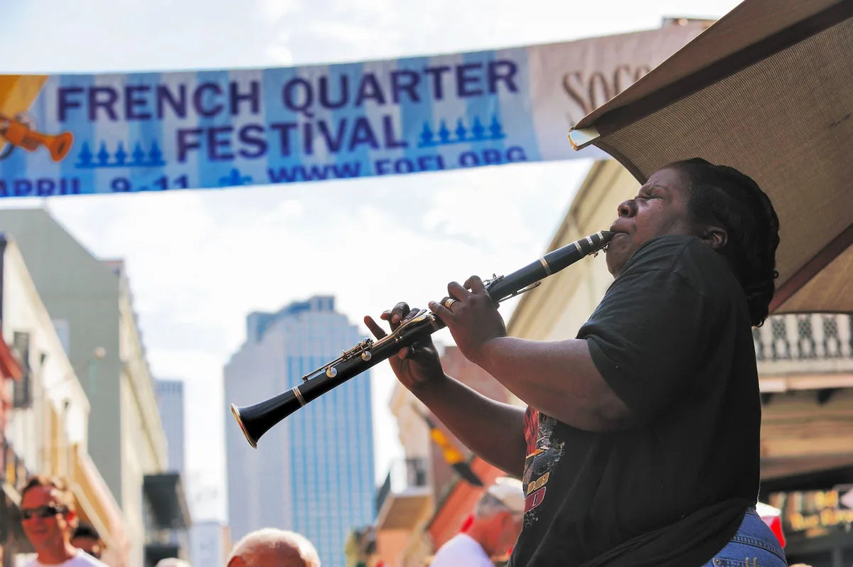 Person playing clarinet with New Orleans French Quarter festival banner in the background