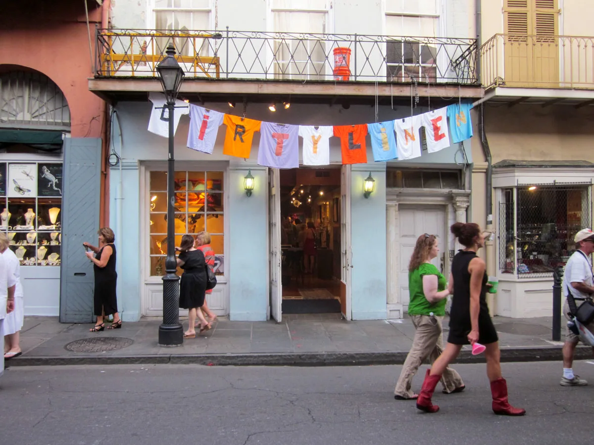 People walking down the street in front of a shop with a Dirty Linen banner out front. Part of the Dirty Linen festival in New Orleans.