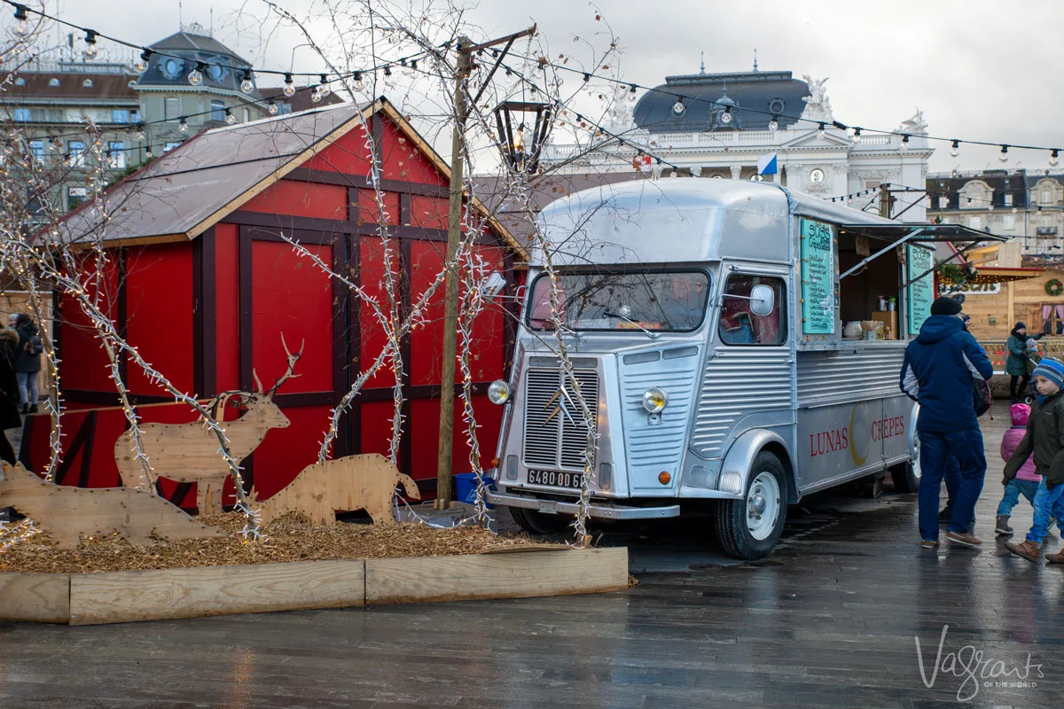 Zurich Christmas markets. A silver food van parked in front of bright red Christmas huts. 
