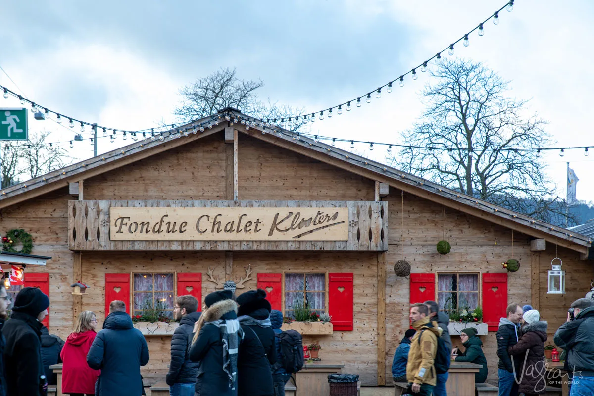 people walking in front of a wooden building - Fondue Chalet at the Zurich Christmas Markets