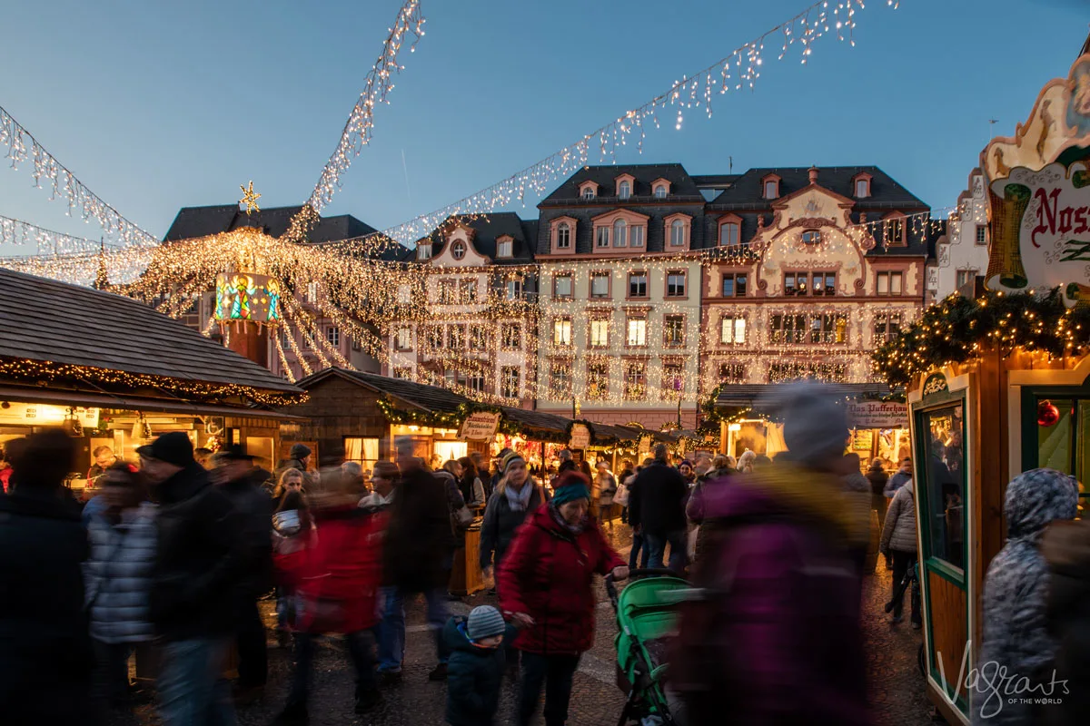 people at the Mainz Christmas markets at night with the lights all lit. 