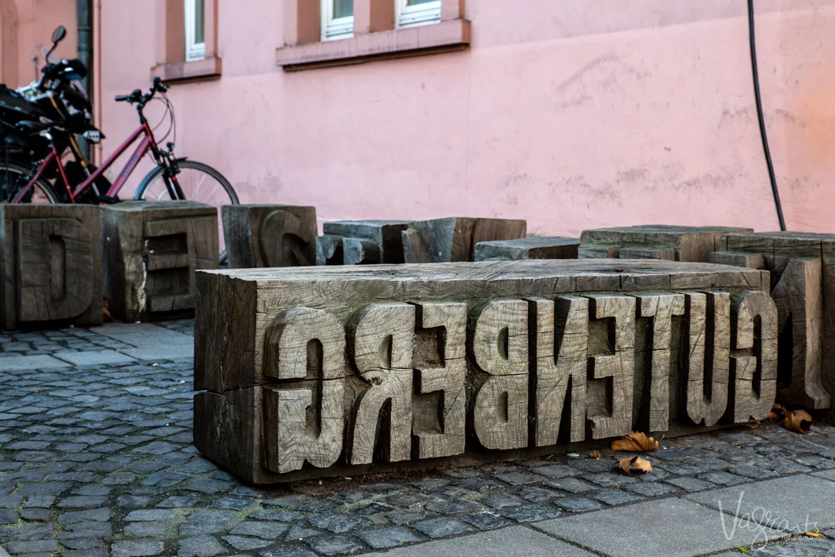 Carved timber sign that reads Gutenberg backwards in the style of the printing press he invented. The Gutenberg museum is one of the stops on a Rhine river cruise. 