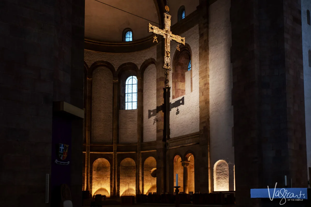 Interior of Speyer cathedral in Speyer Germany. looking up at the main cross over the alter with the shadow of the cross on the back wall with lit alcoves. 