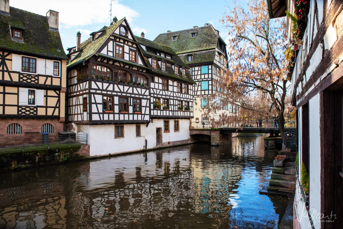 Looking over the canals at the brightly coloured wooden houses reflecting in the water in Strasbourg France. One of the best stops on the Rhine river cruise for the best Christmas markets in Europe. 