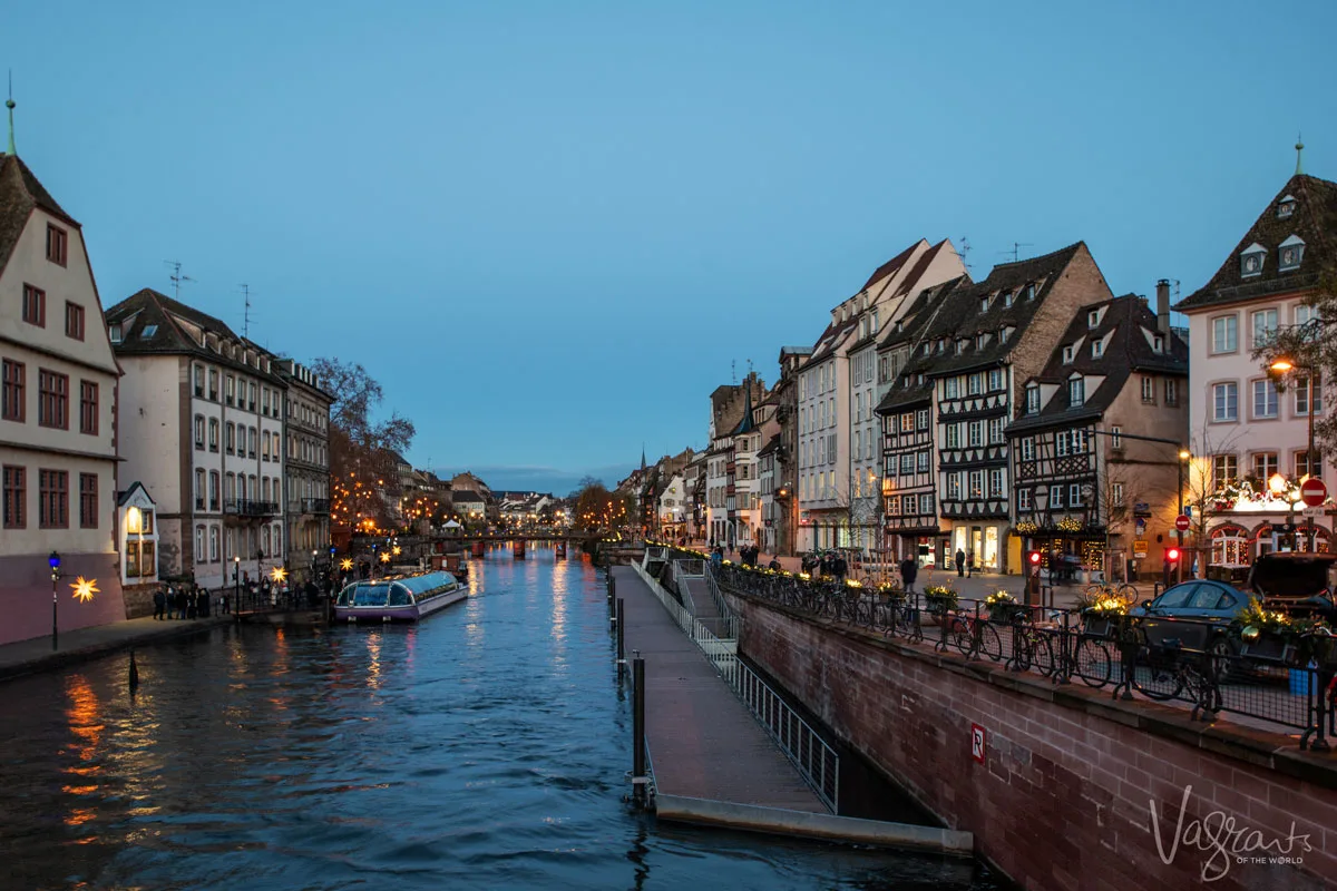Looking down the canals in Strasbourg France at night with the buildings brightly lit either side