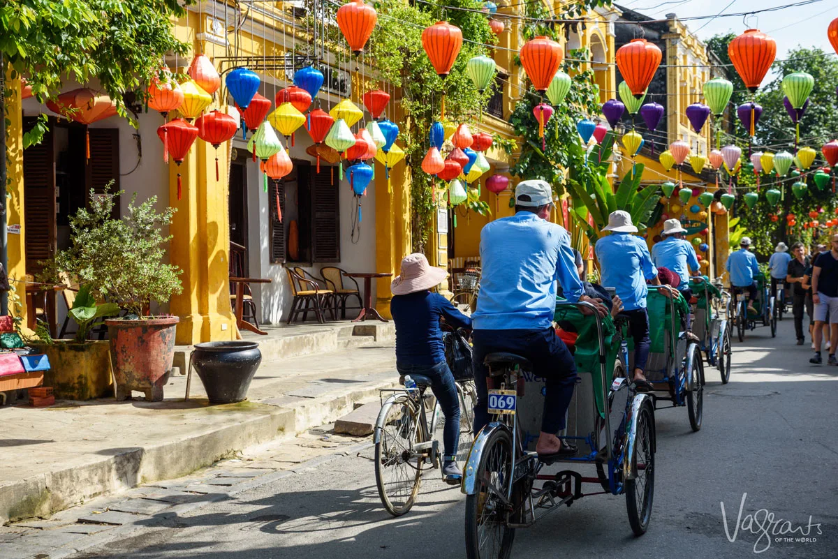 A line of cyclo drivers riding into the brightly coloured, lantern filled streets of Old Town Hoi An