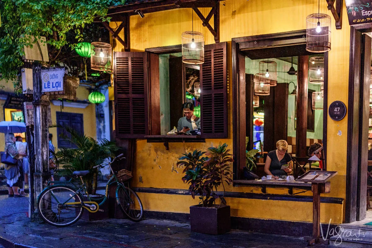 A man and lady sitting in separate windows in a pretty Hoi An cafe in Le Loi Street, Old Town