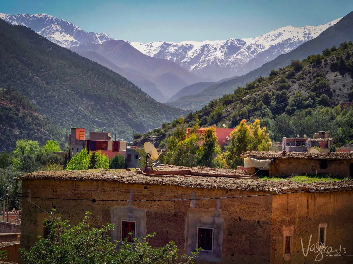 Valley in Morocco with snow capped Atlas Mountains and mud brick house.