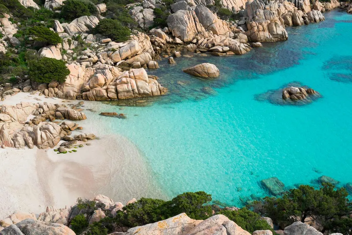 Best beach in Sardinia with white sand, clear water in a bay surrounded by rocky cliffs. 