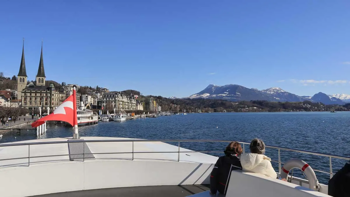 Two people sitting on the foredeck of a luxury yacht on Lake Lucerne Switzerland. A cruise is one of the beat things to do in Lucerne.