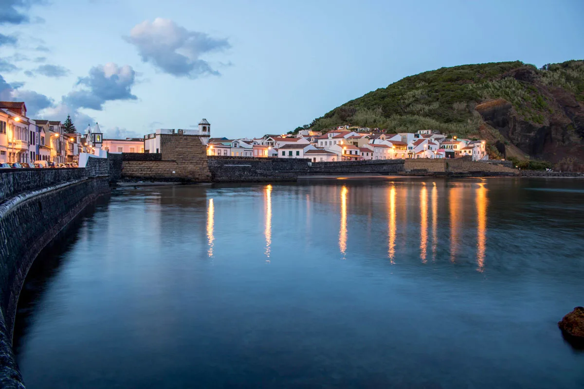 Lit houses and reflections on waterfront in the evening on Faial island.
