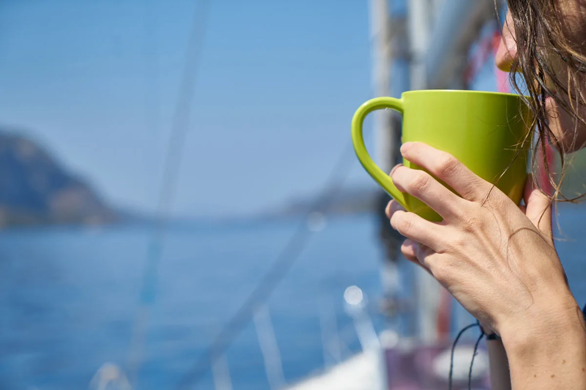  girl enjoying a cup of coffee next to the sea.