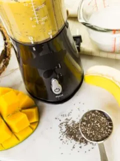 Looking down on a table with mango,banana, and chia seeds cut up for the portable blender.