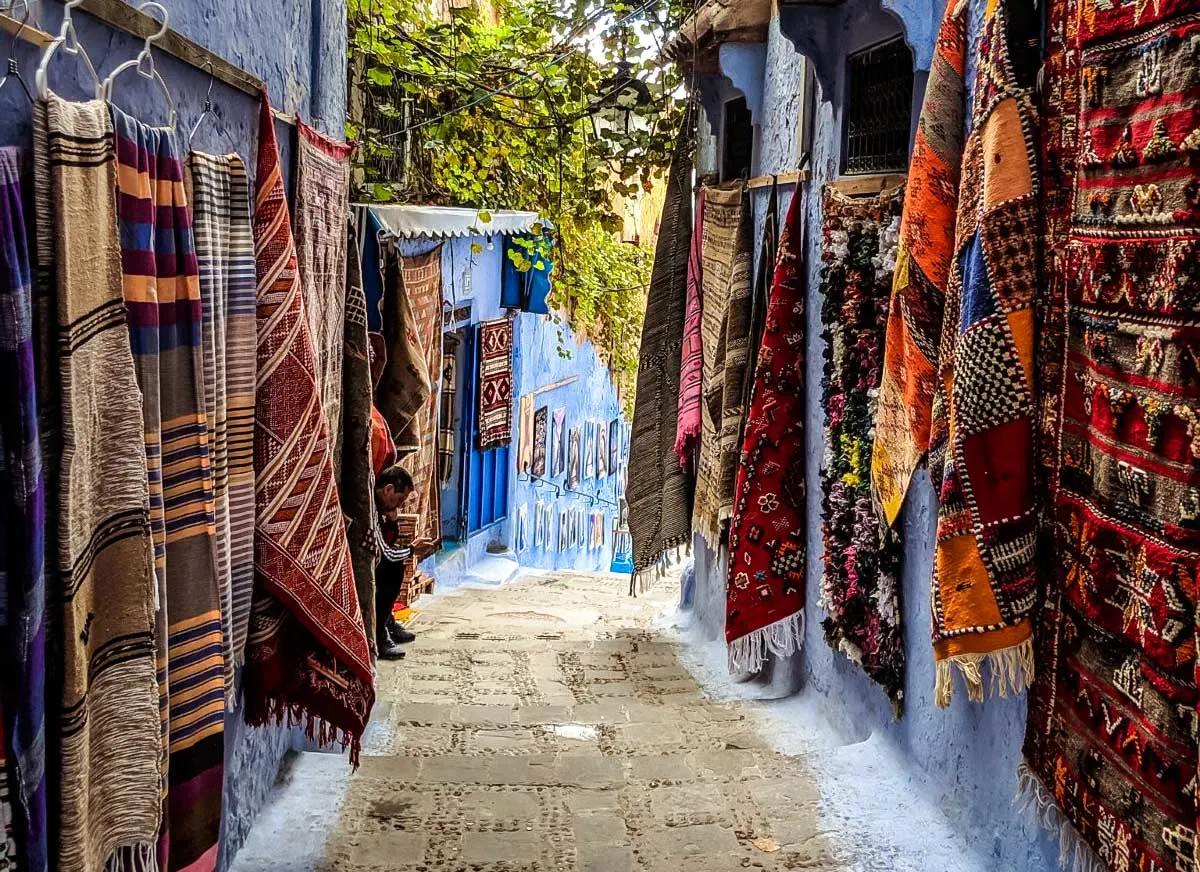 Chefchaouen alley lined with colourful rugs and mats.