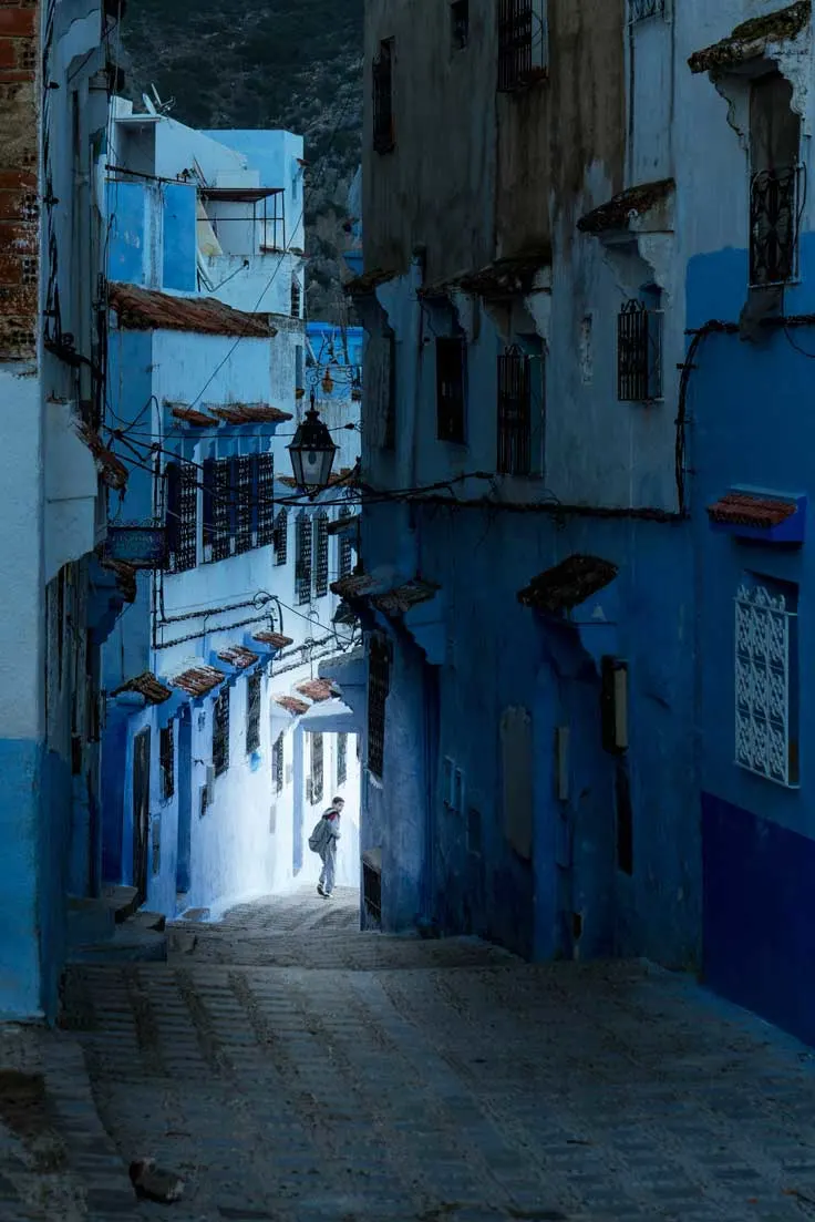 Dark blue, man in alley in Chefchaouen at night.
