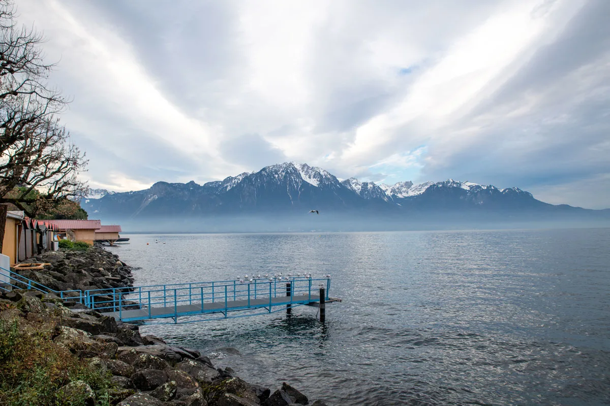 Jetty out into the lake and clouds over the mountains and lake, Montreux