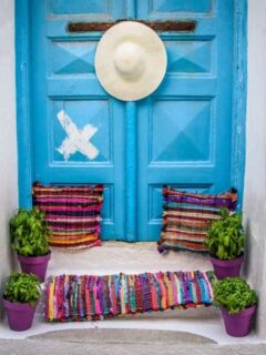 Blue doors and colourful cushions, mat and hat. Chora Old Town Mykonos.