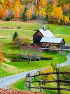 Winding road leading to a farmhouse and autumn trees in fall, New England