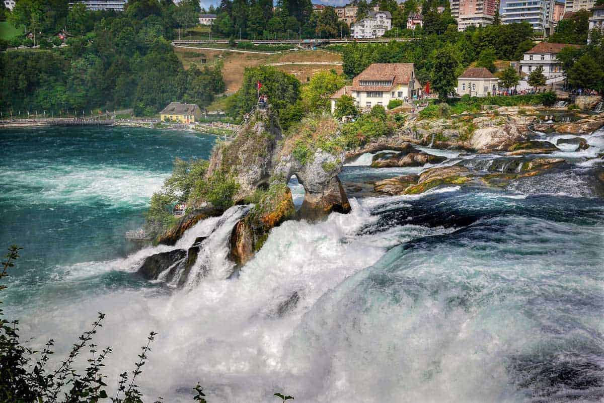 People atop a rock in the middle of the cascading Rhine falls